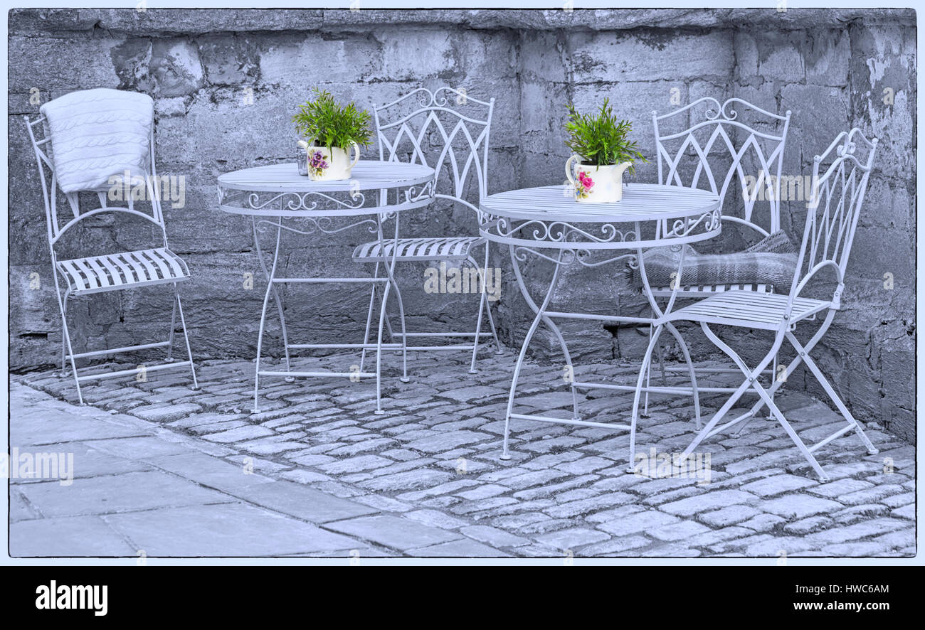 Cirencester - ornato tavoli e sedie in ferro battuto con vasi per piante in un angolo della, Cirencester Gloucestershire in Marzo Foto Stock