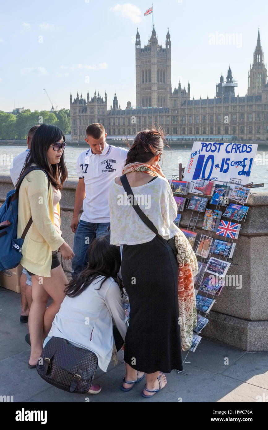 Giovani turisti del Regno Unito. Persone che scelgono le cartoline per la vendita da parte del fiume Tamigi a Londra, Inghilterra, Regno Unito Foto Stock
