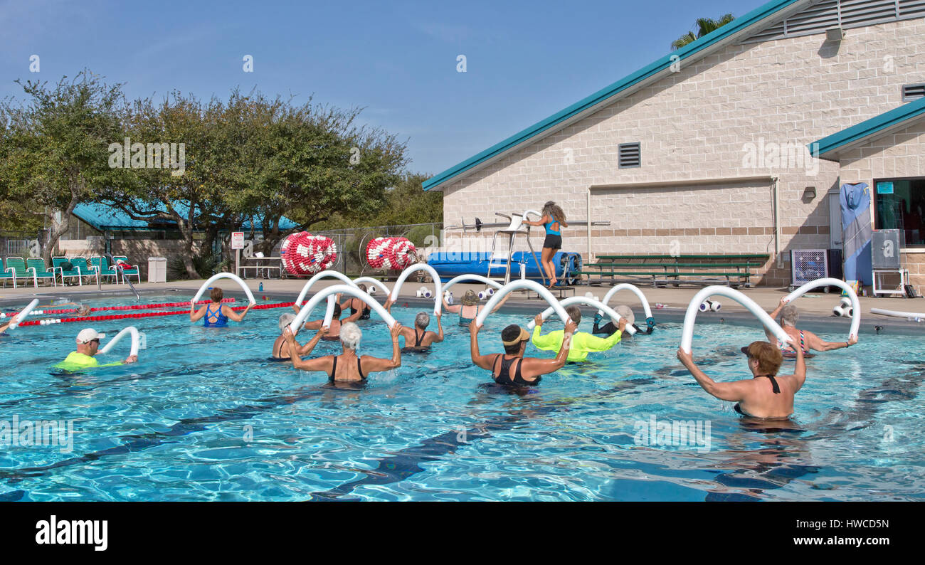 Il gruppo di donne, 1 uomo, compresi gli anziani, frequentando aerobica, acqua gym, istruttore dimostrando, utilizzando styrofoam 'acqua a base di noodle'. Foto Stock