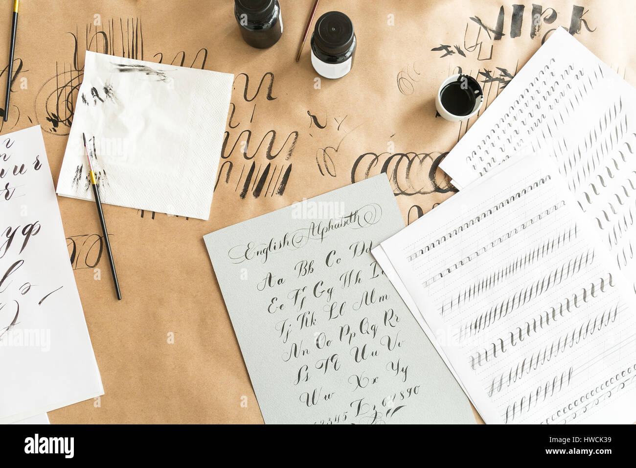 La calligrafia fogli, naselli, carta, inchiostro e le penne su un sfondo kraft. Lettering Workshop di calligrafia. apprendimento calligraphy - carta con l esempio e con pennello e inchiostro. Concetto hobby. Foto Stock