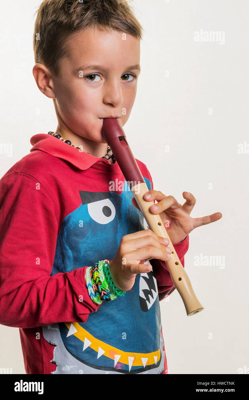 Un bambino gioca su un flauto di legno. Educazione musicale e scuola di musica., Ein tipo spielt auf einer Flöte auf Holz. Musikerziehung und Musikschule. Foto Stock