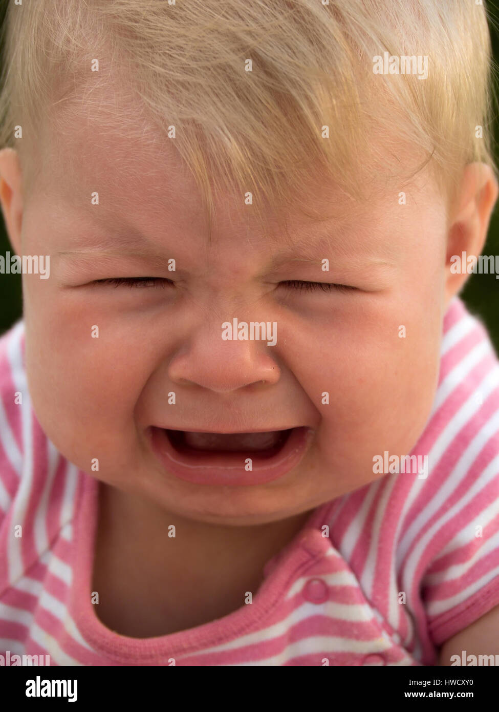 Gridando bambino giace su un prato ed è triste, Weinendes Baby liegt auf einer Wiese und traurig ist Foto Stock