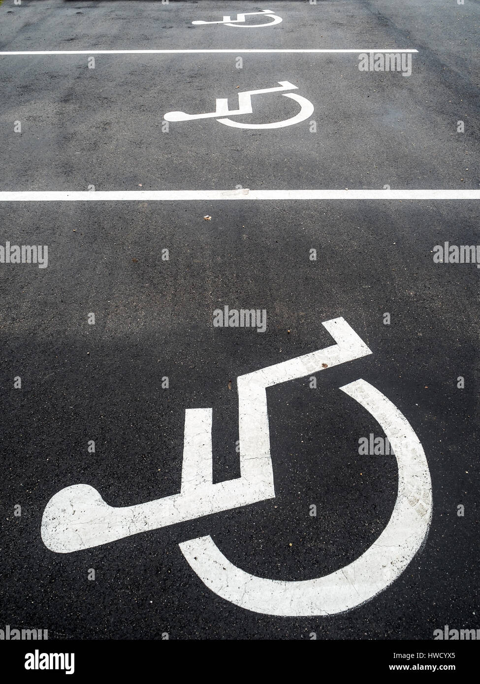 Una sedia a rotelle si trova proprio su una baia di parcheggio per disabili., Ein Rollstuhl ist auf einem Parkplatz für Behinderte angebracht. Foto Stock
