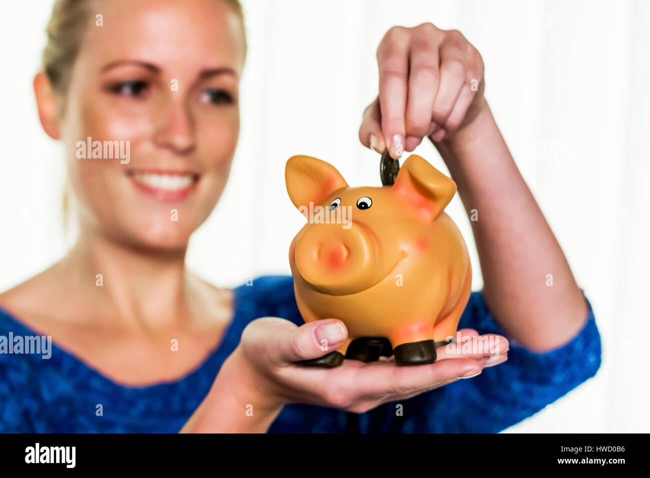 Una giovane donna detiene un modo divertente di maiale nella sua mano. Foto simbolico messo su per scherzi, il denaro e la vecchiaia disposizioni., Eine junge Frau h‰lt ein Sparschwein in ih Foto Stock