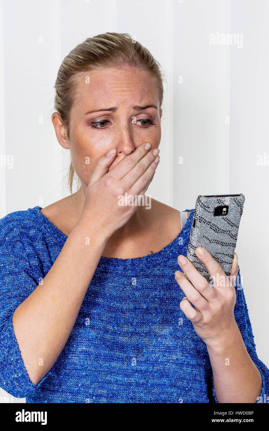 Una donna riceve cattive notizie da SMS ed è sconvolto., Eine Frau bekommt schlechte Nachrichten per SMS und ist geschockt. Foto Stock