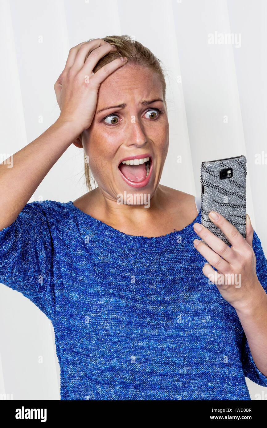 Una donna riceve cattive notizie da SMS ed è sconvolto., Eine Frau bekommt schlechte Nachrichten per SMS und ist geschockt. Foto Stock