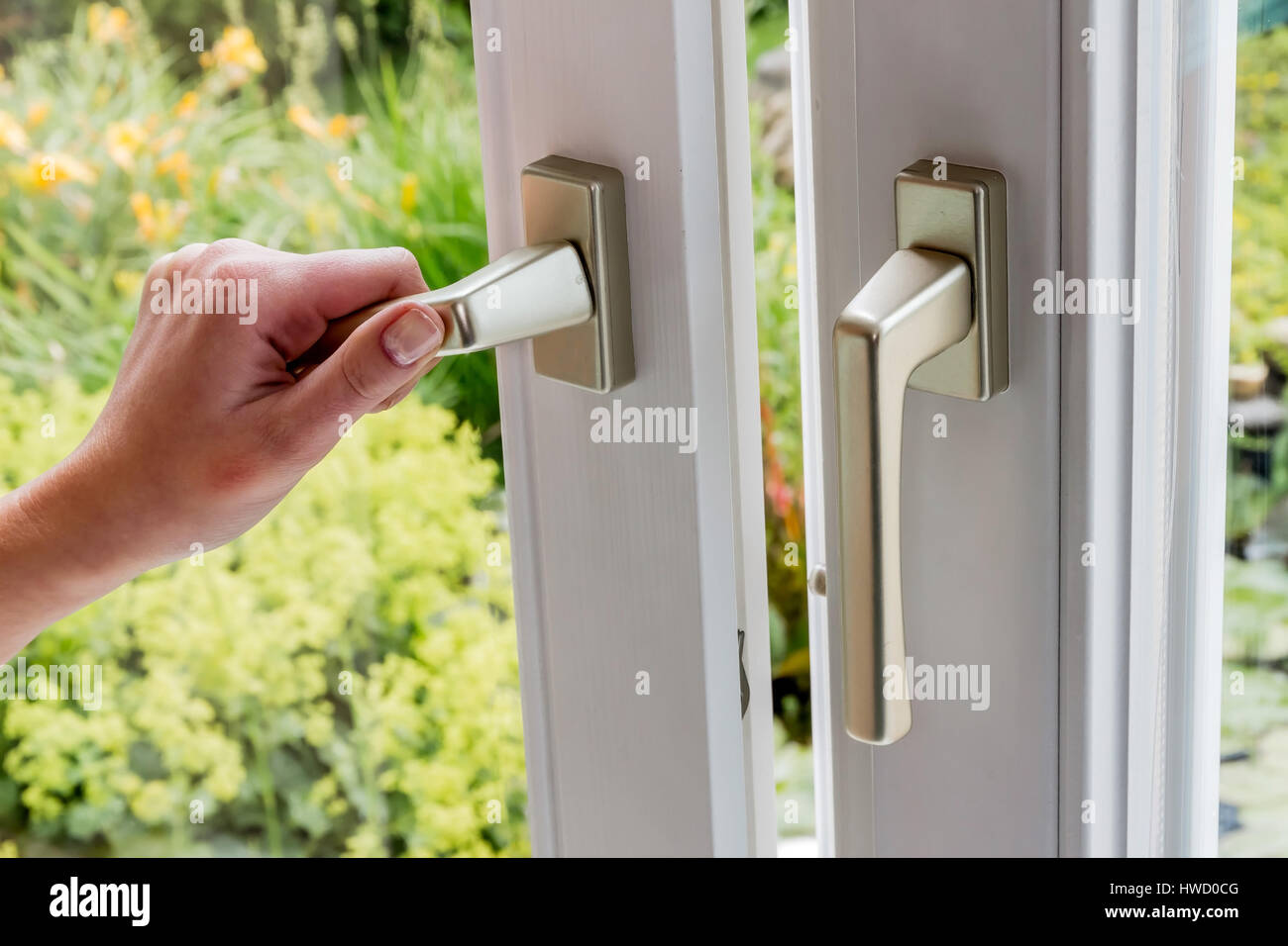 Una donna si apre una finestra per i venti del piatto. Aria fresca in camera, Eine Frau ˆffnet ein Fenster zum L'ften der Wohnung. Frische Luft im Zimmer Foto Stock