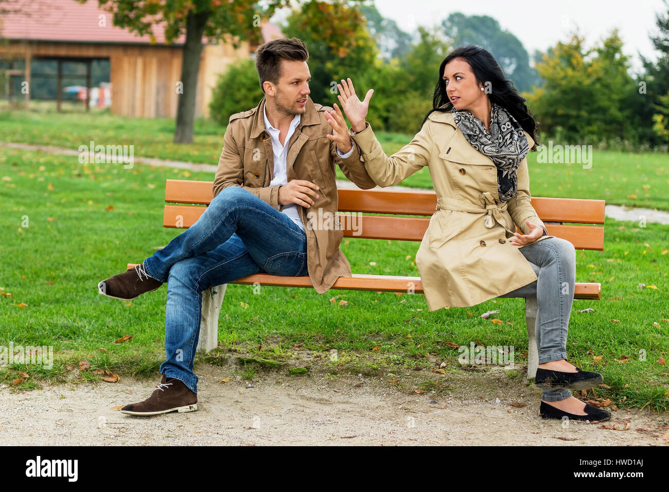 Una giovane coppia si siede su un parco-banco e sostiene, Ein junges Paar sitzt auf einer Parkbank und streitet Foto Stock