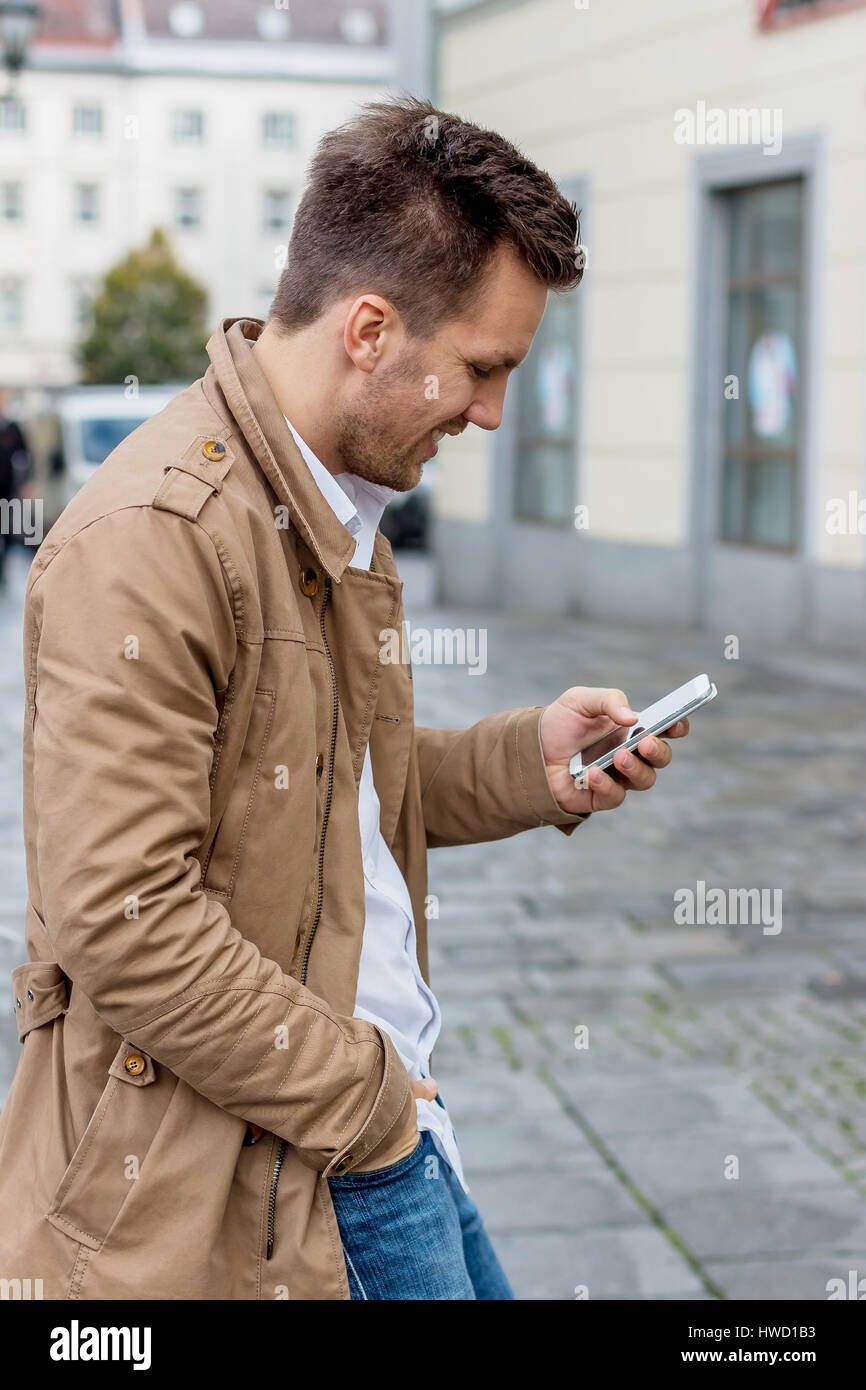 Un uomo scrive un SMS sul suo telefono cellulare. La comunicazione con uno smart phone, Ein Mann schreibt auf seinem Handy ein SMS. Kommunikation mit einem Smart p Foto Stock