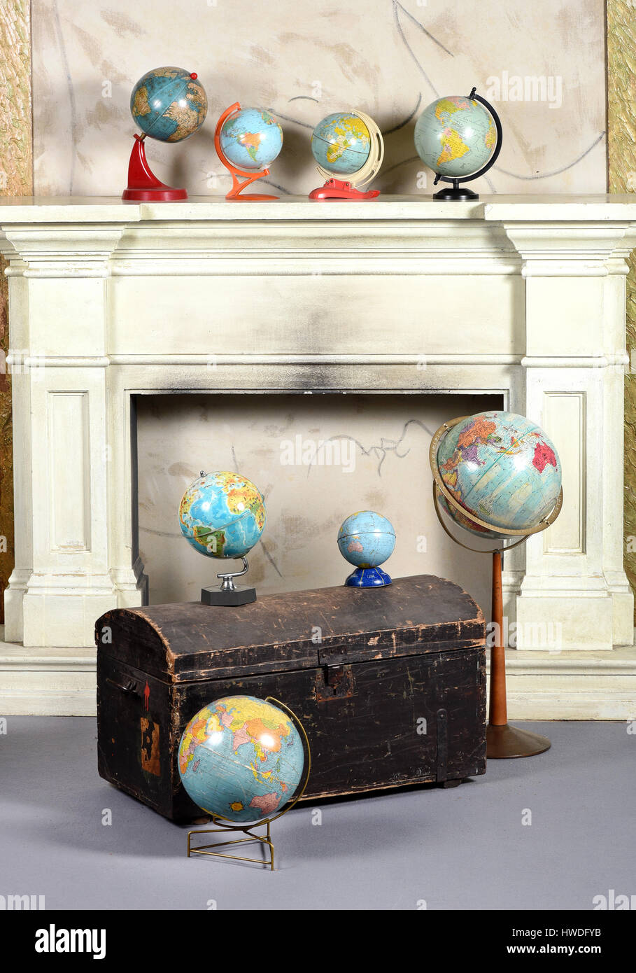 Vecchio martoriata torace a cupola o tronco con una collezione di vintage assortiti globi davanti a un caminetto Foto Stock