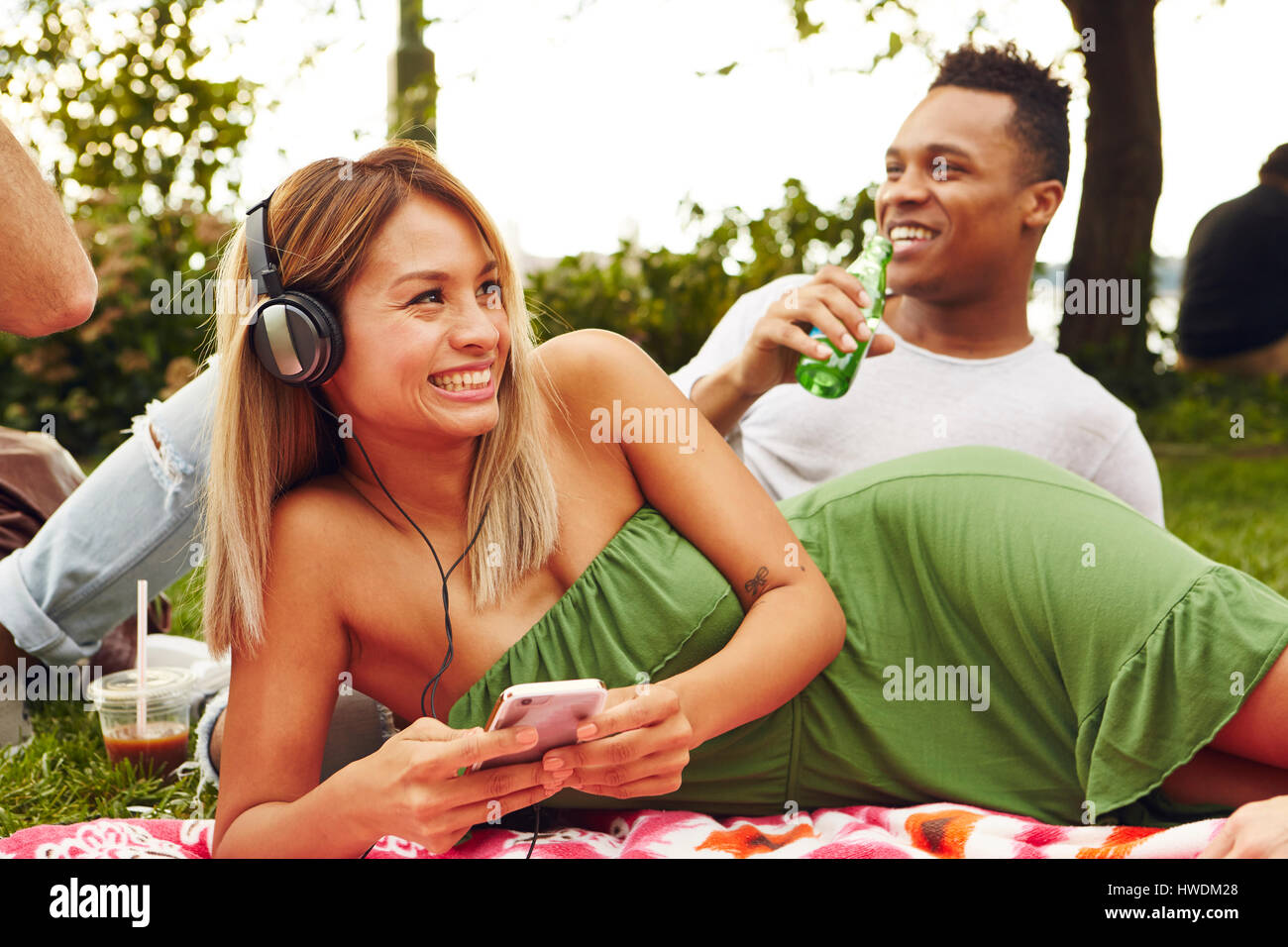 Donna scegliendo la musica sullo smartphone mentre fare picnic nel parco Foto Stock