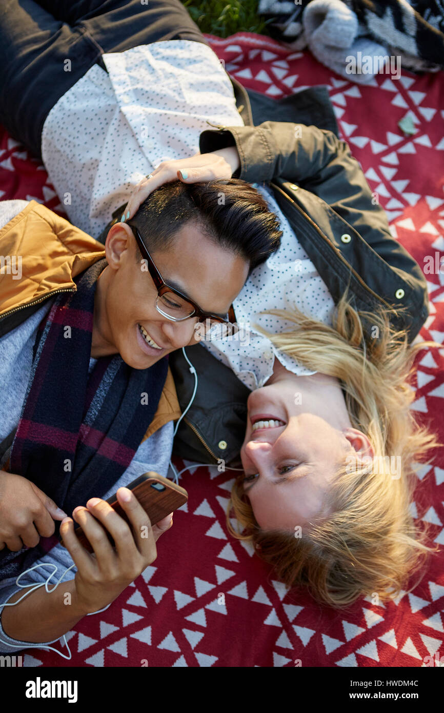 Vista aerea del giovane sulla coperta picnic condivisione musica auricolare Foto Stock
