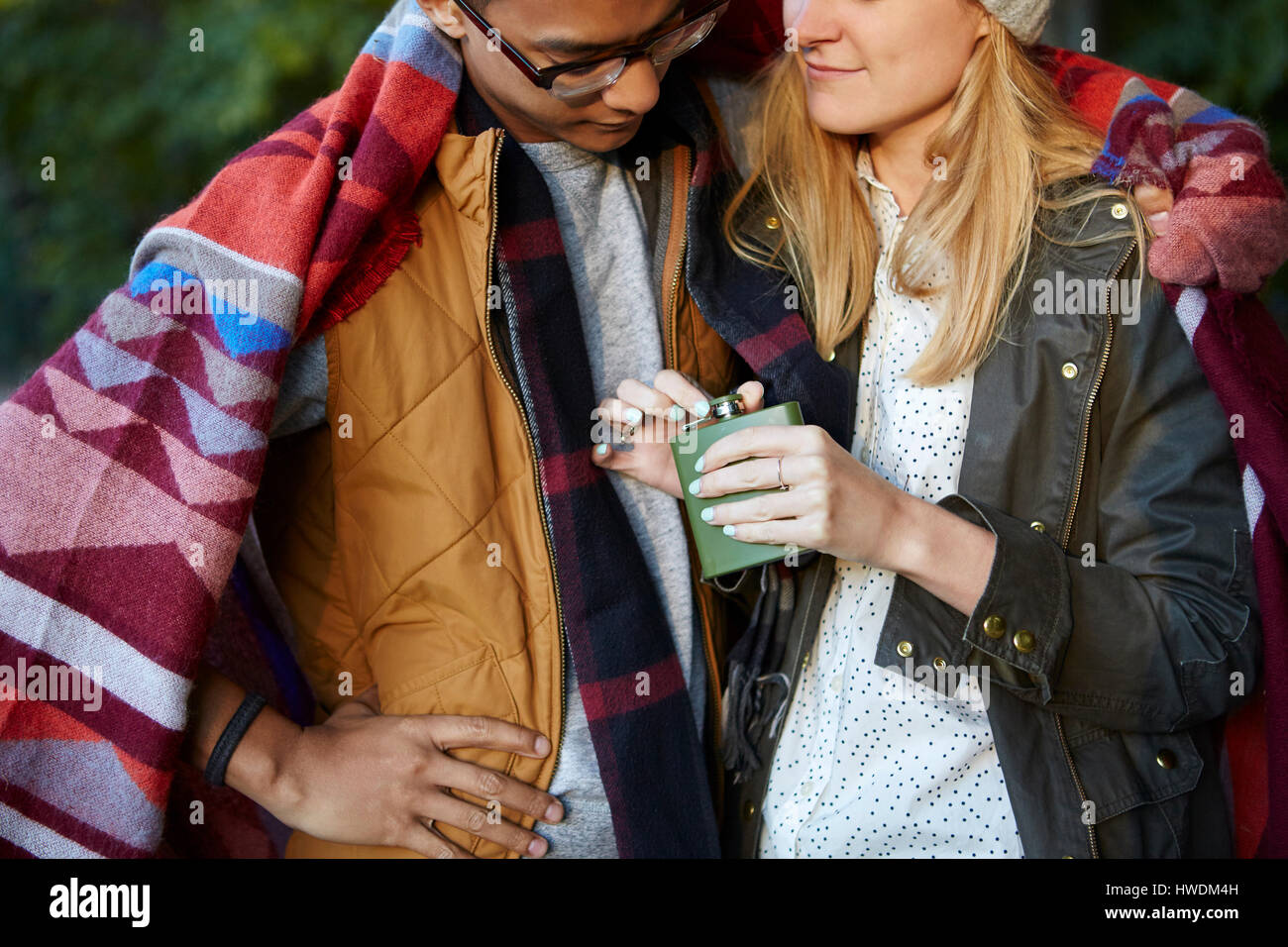 Ritagliato colpo di giovane avvolto in una coperta, apertura fiaschetta in posizione di parcheggio Foto Stock