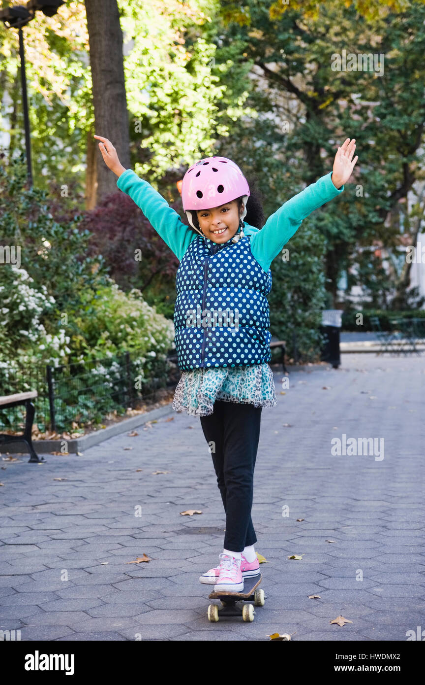 Ragazza di skateboard a braccia alzate sorridente, New York, Stati Uniti d'America Foto Stock