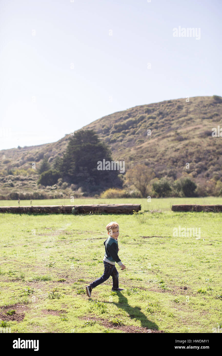 Ragazzo in tutta verde collina in background Foto Stock