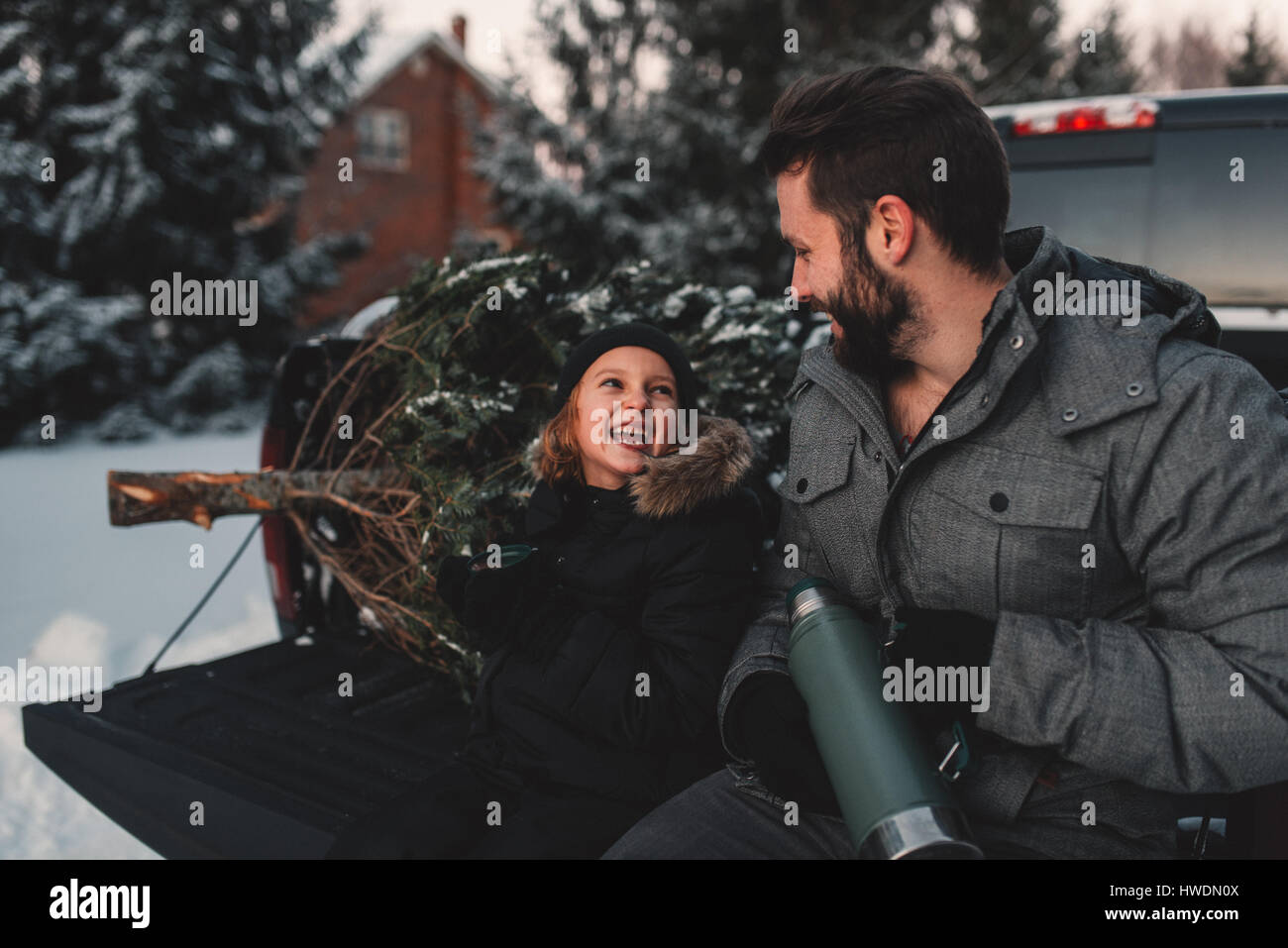 Padre e figlia sul retro del pick up truck con il loro albero di Natale Foto Stock