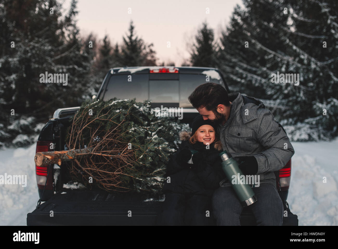 Padre e figlia sul retro del pick up truck con il loro albero di Natale Foto Stock