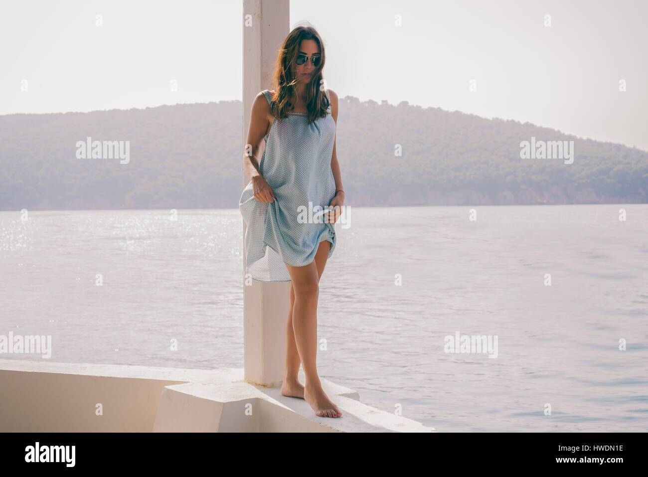 Elegante giovane donna camminando lungo la parete dal mare, Burgaz Isola, Istanbul, Turchia Foto Stock