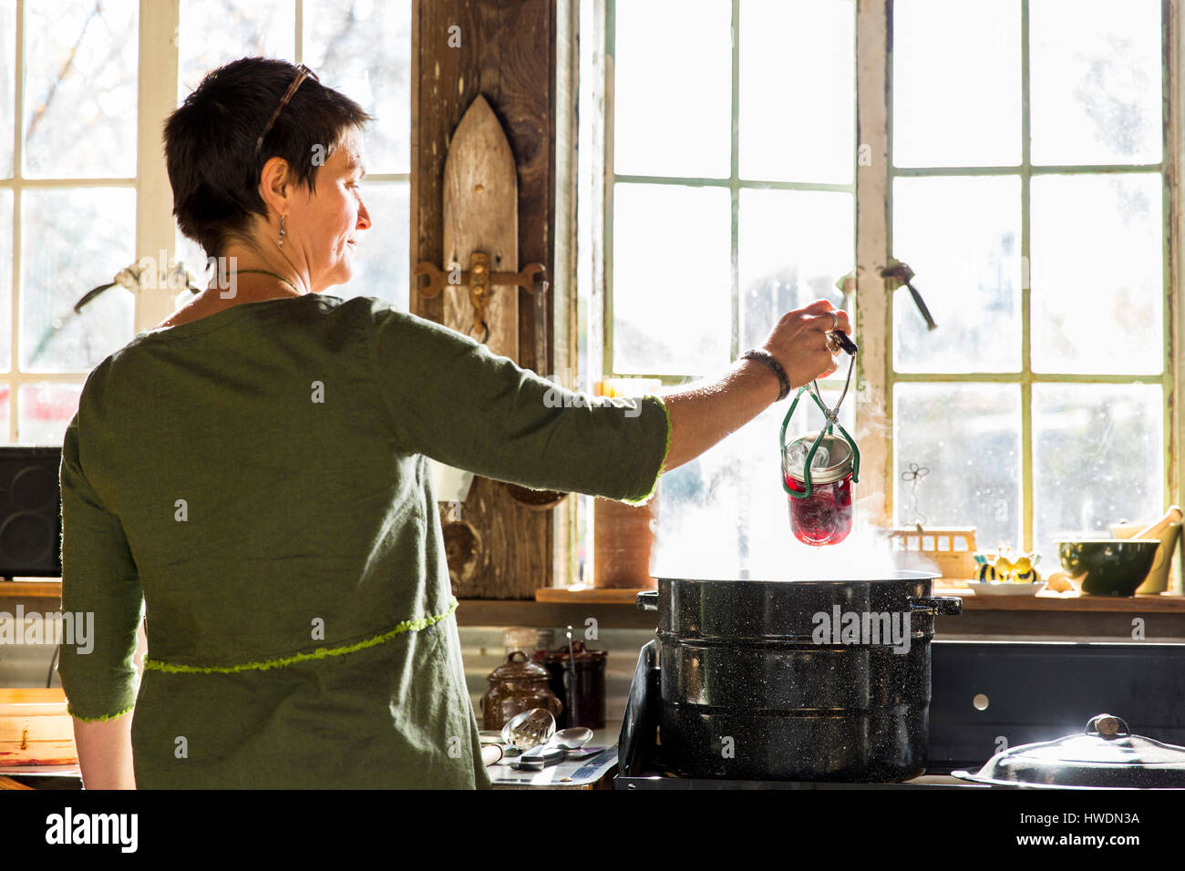 Vista posteriore della donna la rimozione di barbabietole conserva jar dalla pentola di cottura a vapore Foto Stock