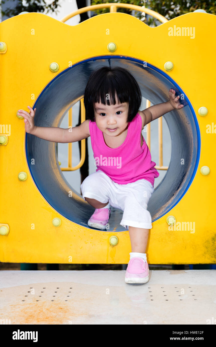 Asian poco ragazza cinese giocando in un tubo al parco giochi. Foto Stock