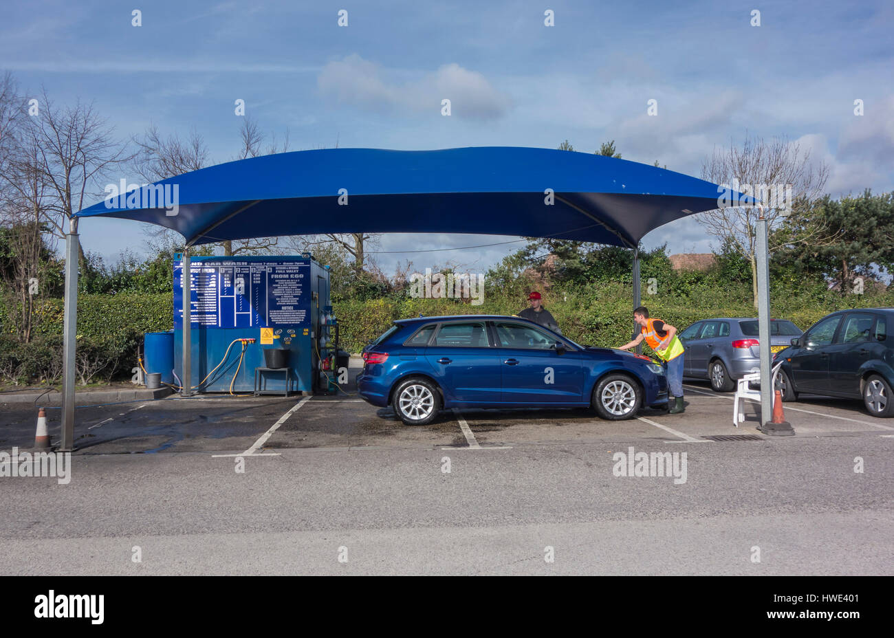 Una vettura che viene pulita in un autolavaggio manuale unità in un parcheggio in Poole, Dorset, Regno Unito Foto Stock