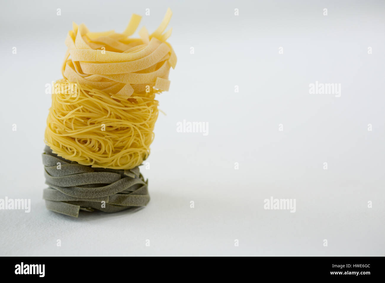 Pila di tagliatelle e capellini pasta su sfondo bianco Foto Stock