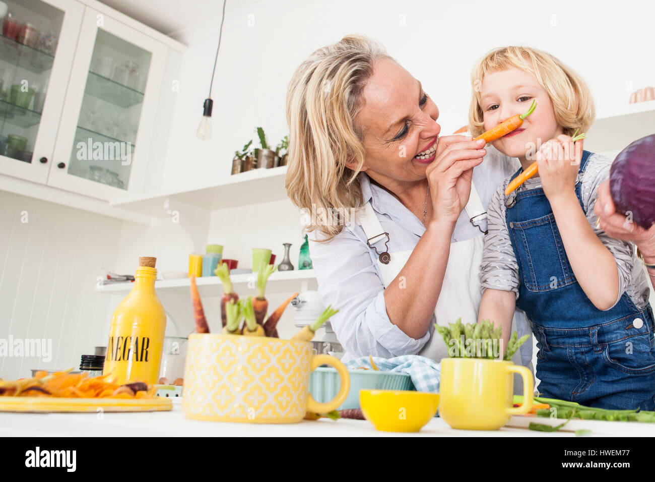 Donna matura rendendo figlia una carota i baffi al tavolo della cucina Foto Stock