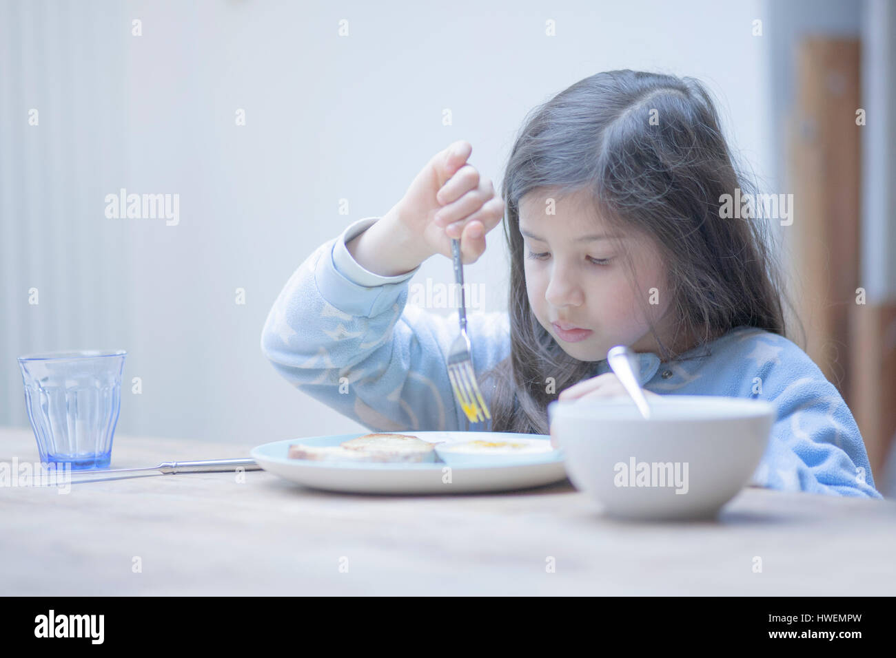 Ragazza mangiare Uovo affogato prima colazione al tavolo della cucina Foto Stock