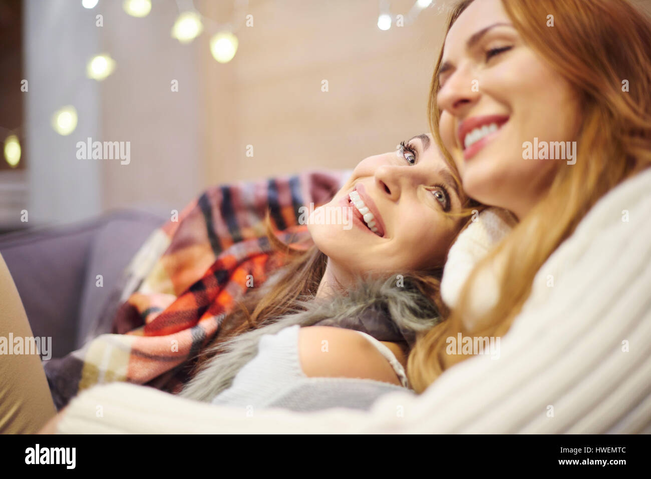 Amici godendo di essere insieme sul divano in chalet Foto Stock