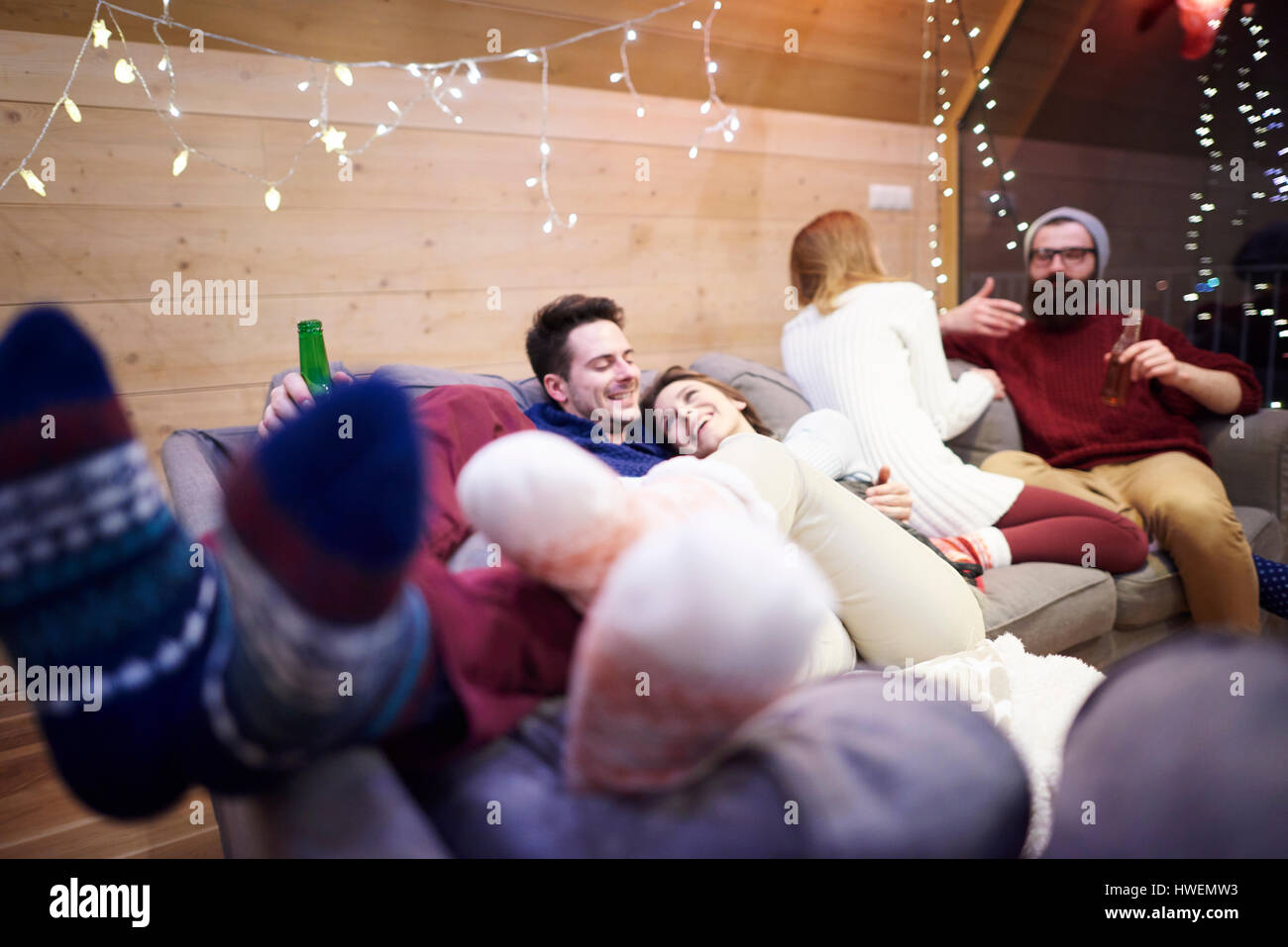 Amici godendo di essere insieme sul divano in chalet Foto Stock