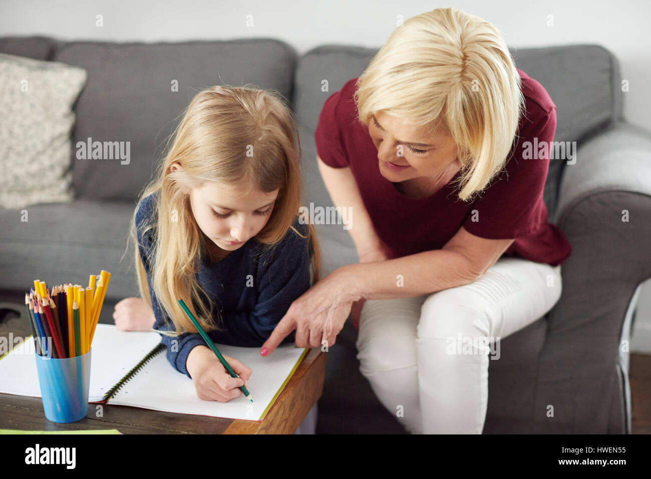 Nonna aiutando la nipote con colorazione a casa Foto Stock