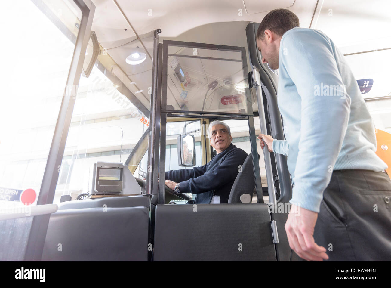 Autista di autobus con passeggeri di salire a bordo del bus elettrico Foto Stock
