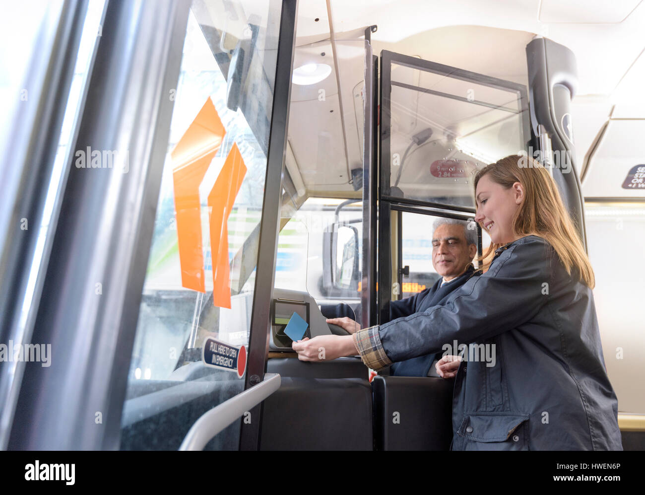 Autista di autobus con passeggeri viaggi swipe card sul bus elettrico Foto Stock