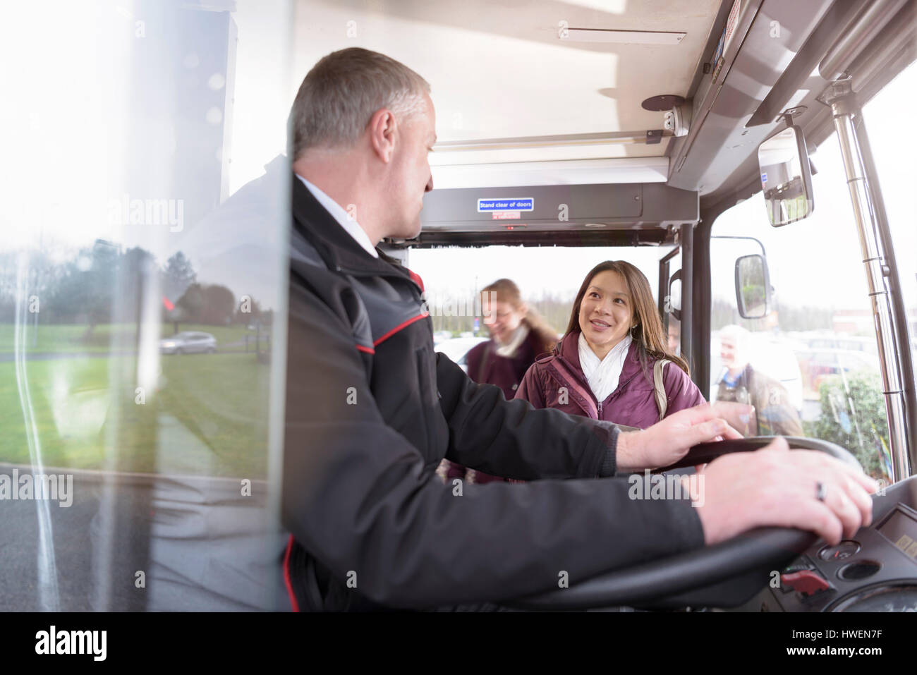 Autista di autobus con passeggeri di salire a bordo del bus elettrico Foto Stock