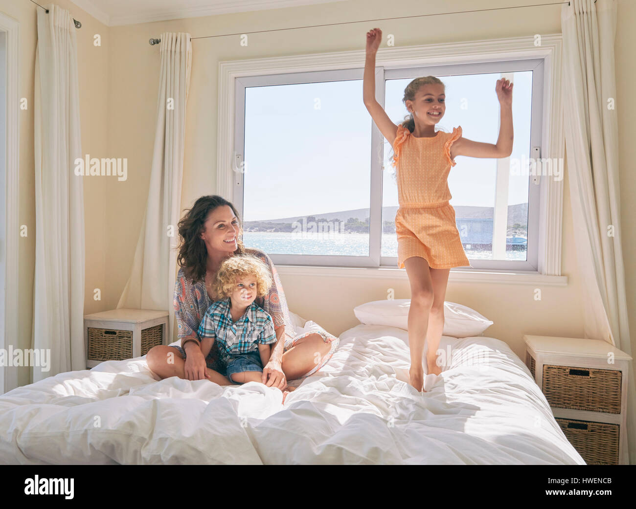 La madre e il figlio guardando la ragazza saltando sul letto Foto Stock