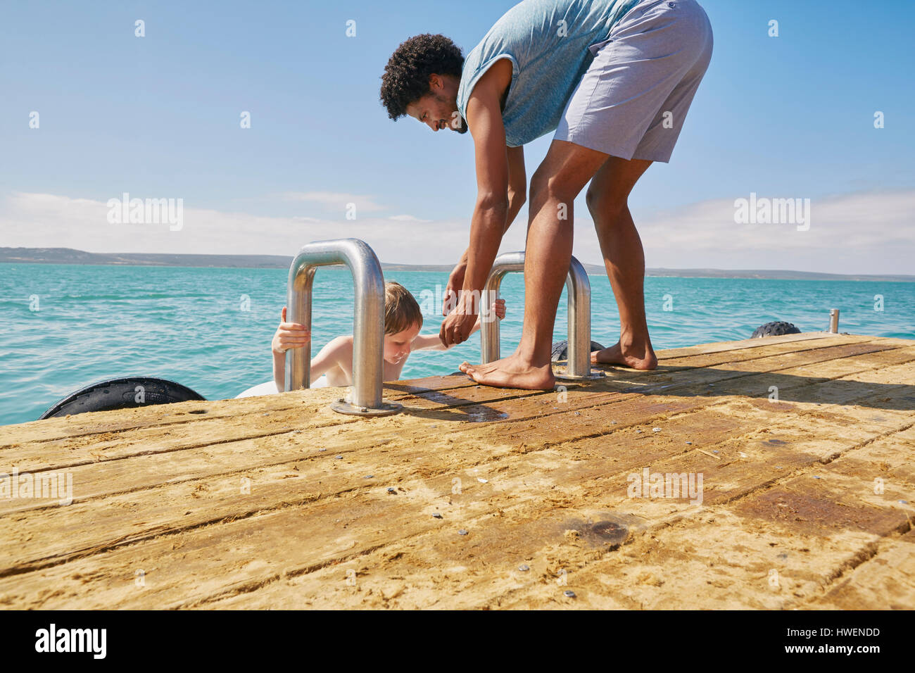 Padre aiutando figlio salire su houseboat sun deck Foto Stock