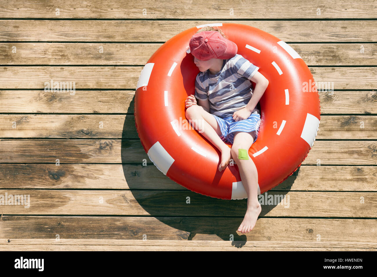 Bambino addormentato in un anello in gomma sul decking, Kraalbaai, Sud Africa Foto Stock