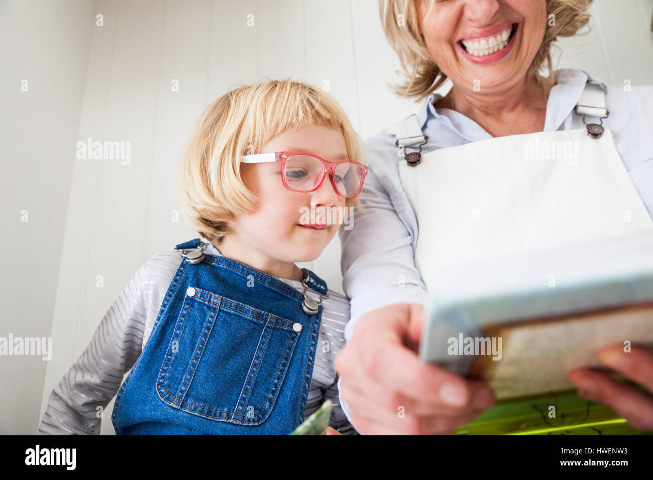 Donna matura seduta sul banco di cucina lettura storybook con la figlia Foto Stock