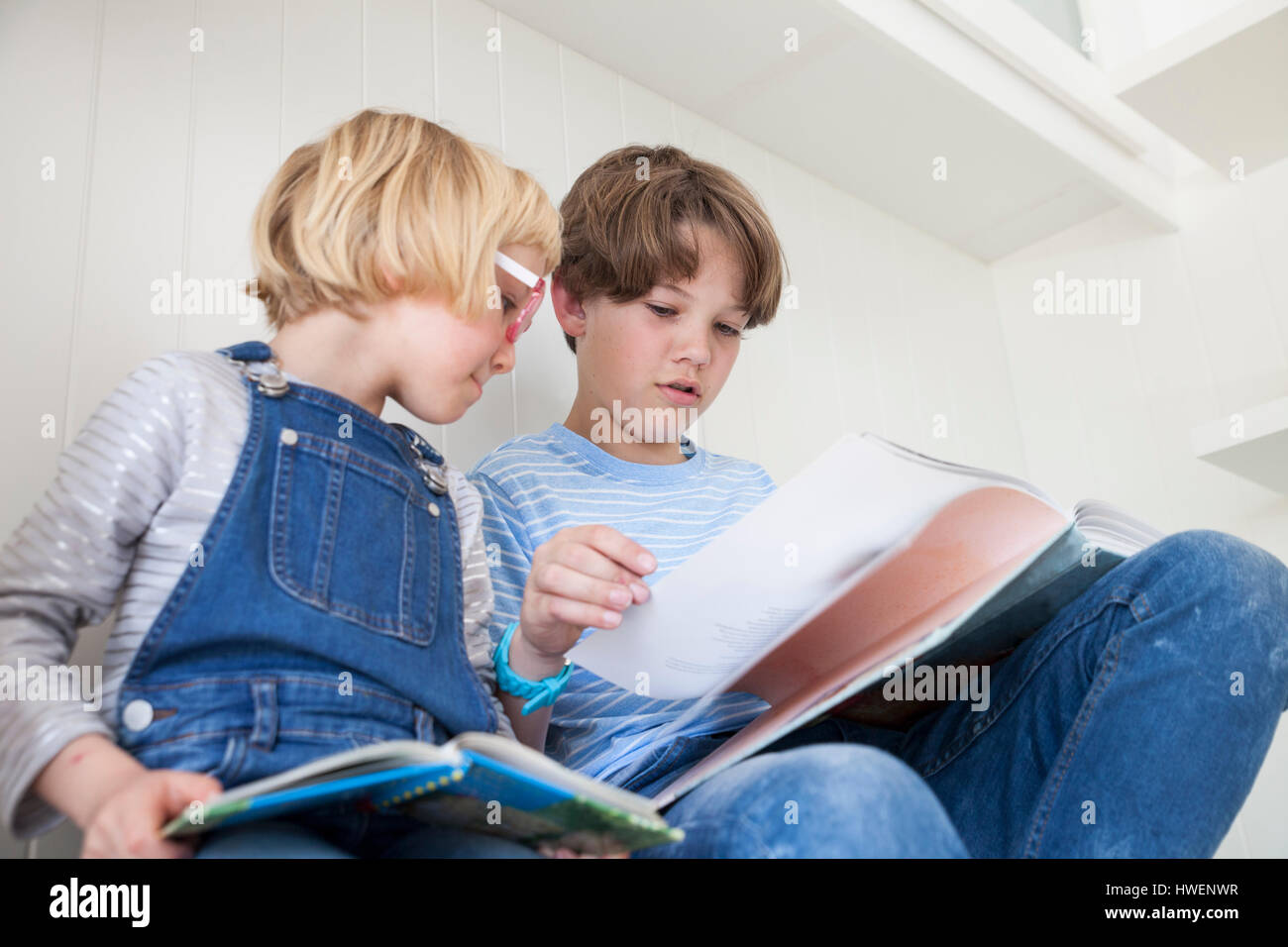 Lettura della ragazza storybook con il fratello sul banco di cucina Foto Stock