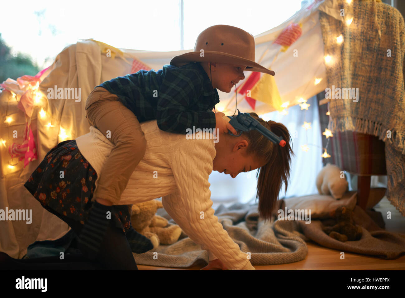 Ragazzo con il cappello da cowboy getting piggyback ride da sorella Foto Stock