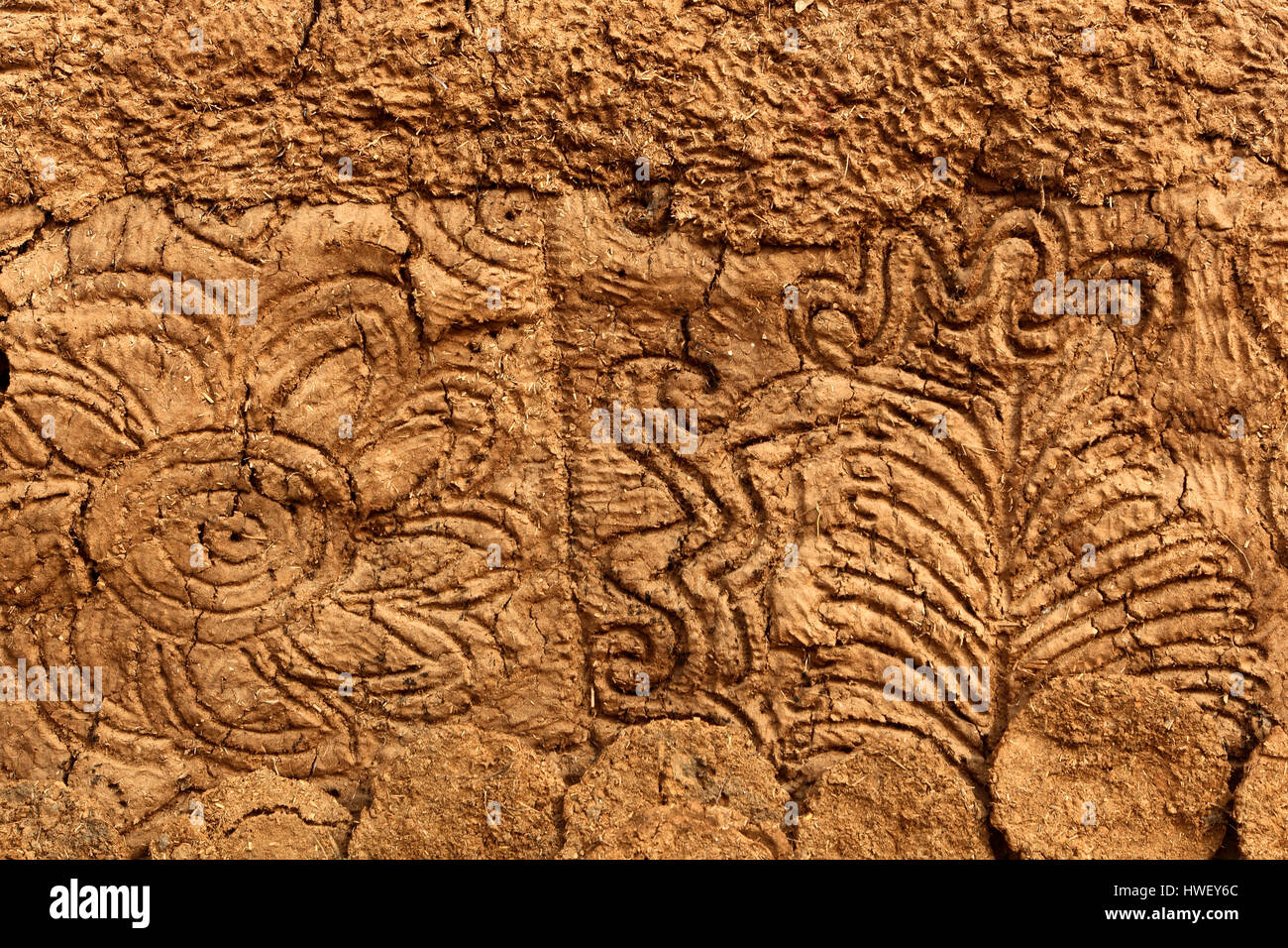 Motivi di sfondo e le texture del design floreale sul fango e paglia a parete di un tradizionale di sterco di vacca negozio di carburante nelle zone rurali del Rajasthan in India del Nord. Foto Stock