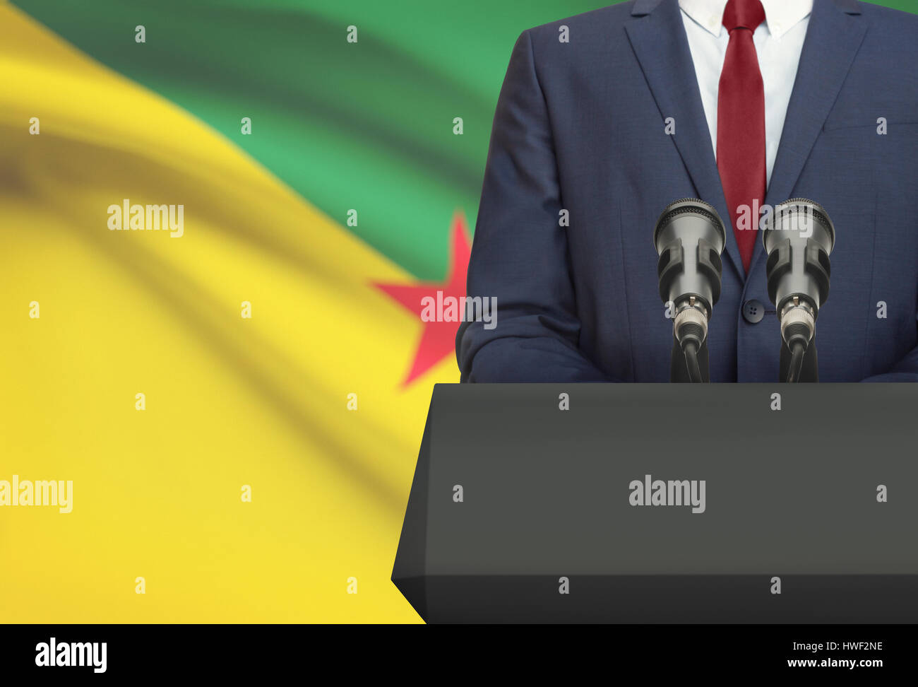 Imprenditore o politico rendono la conversazione da dietro il pulpito con bandiera nazionale su sfondo - Guyana francese Foto Stock