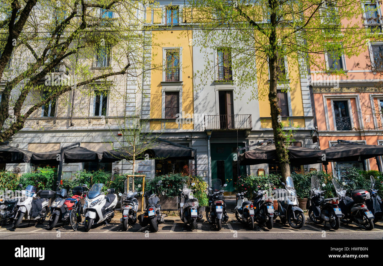 Vespa italiana su un interno occupato e colorata Milano street con caffè e ristoranti Foto Stock