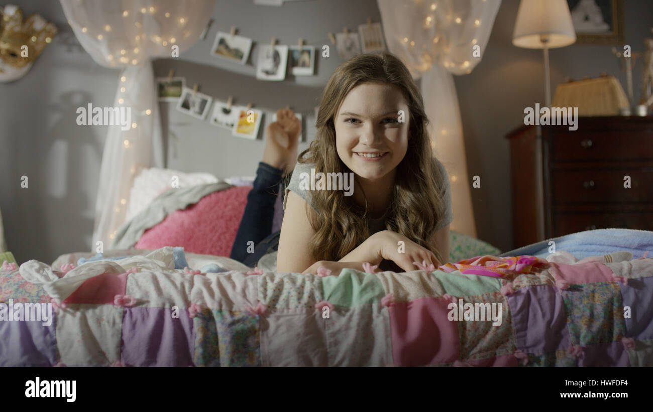 Ritratto di sorridente ragazza adolescente posa sul letto Foto Stock