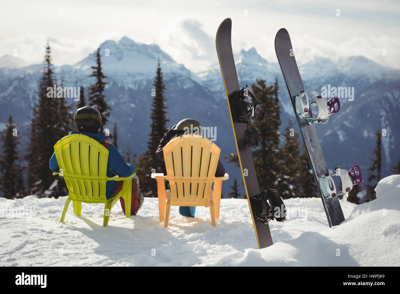 Vista posteriore del giovane seduto su una sedia da snowboard a coperta di neve montagna Foto Stock
