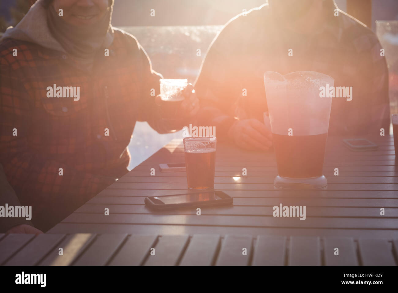 Gli sciatori amici avente un bicchiere di birra in ski resort su una brillante luce solare Foto Stock