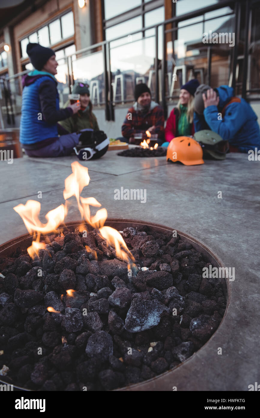 Gruppo di sciatori seduti al posto del fuoco nella stazione sciistica Foto Stock