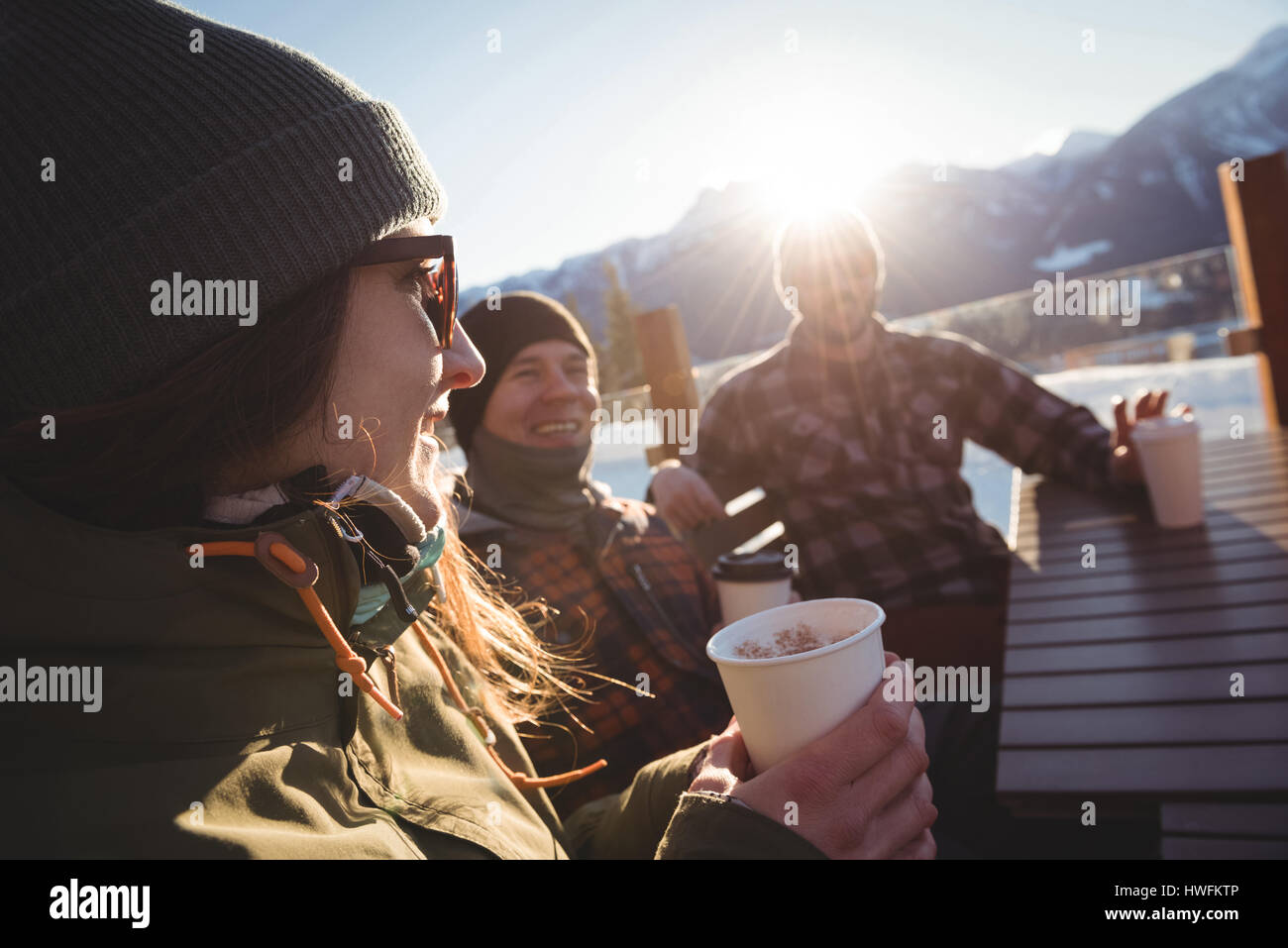 Gli sciatori amici interagire gli uni con gli altri mentre avente tazza di caffè nella stazione sciistica Foto Stock