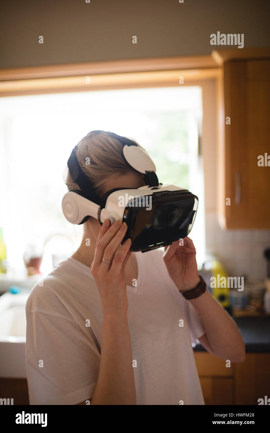 Donna che utilizza la realtà virtuale auricolare a casa Foto Stock