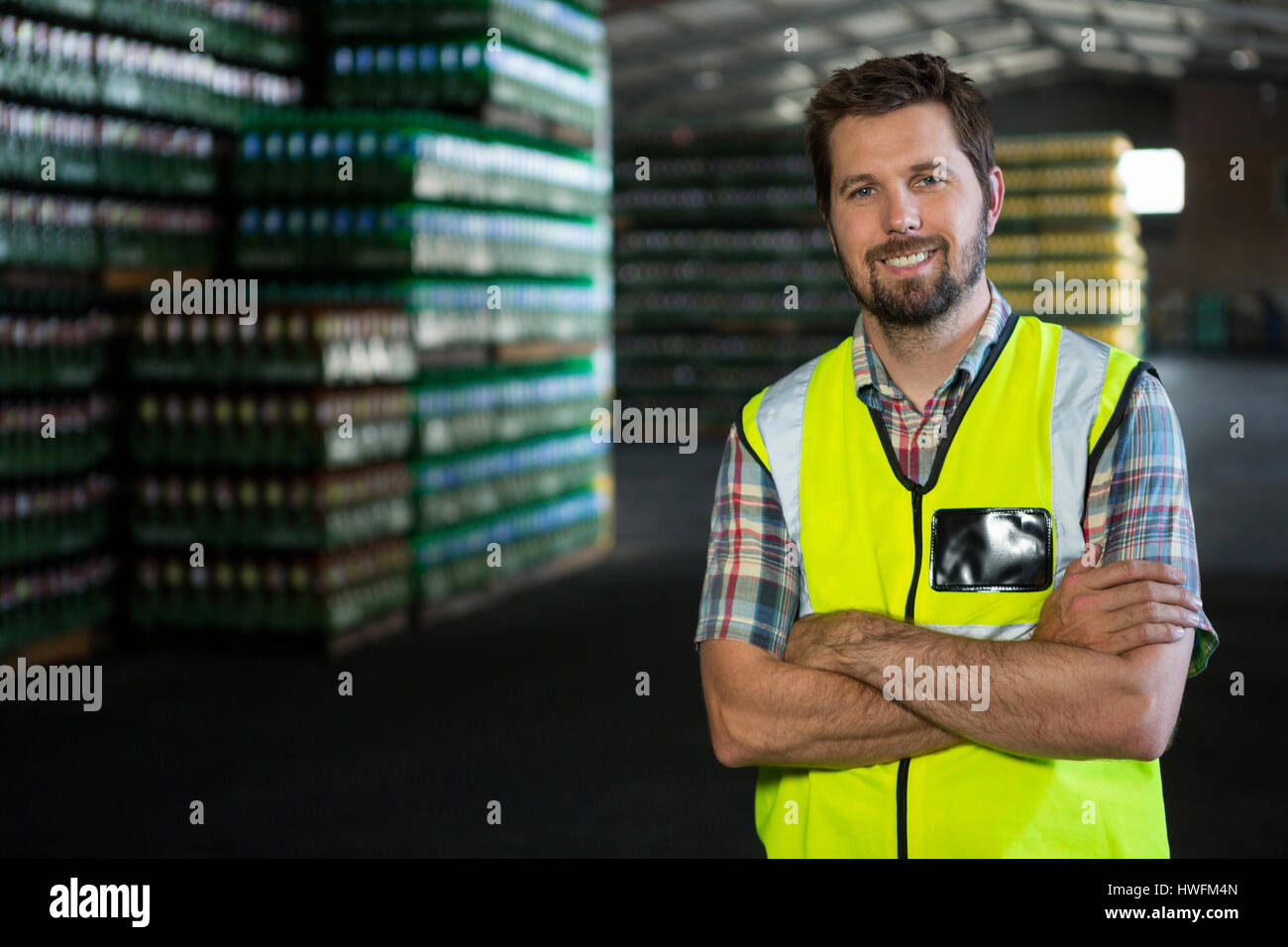 Ritratto di fiducia lavoratore di sesso maschile con le braccia incrociate in piedi in magazzino Foto Stock